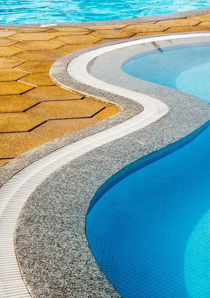 Close-up view of a resort swimming pool with unique curved stone and tile edge design.