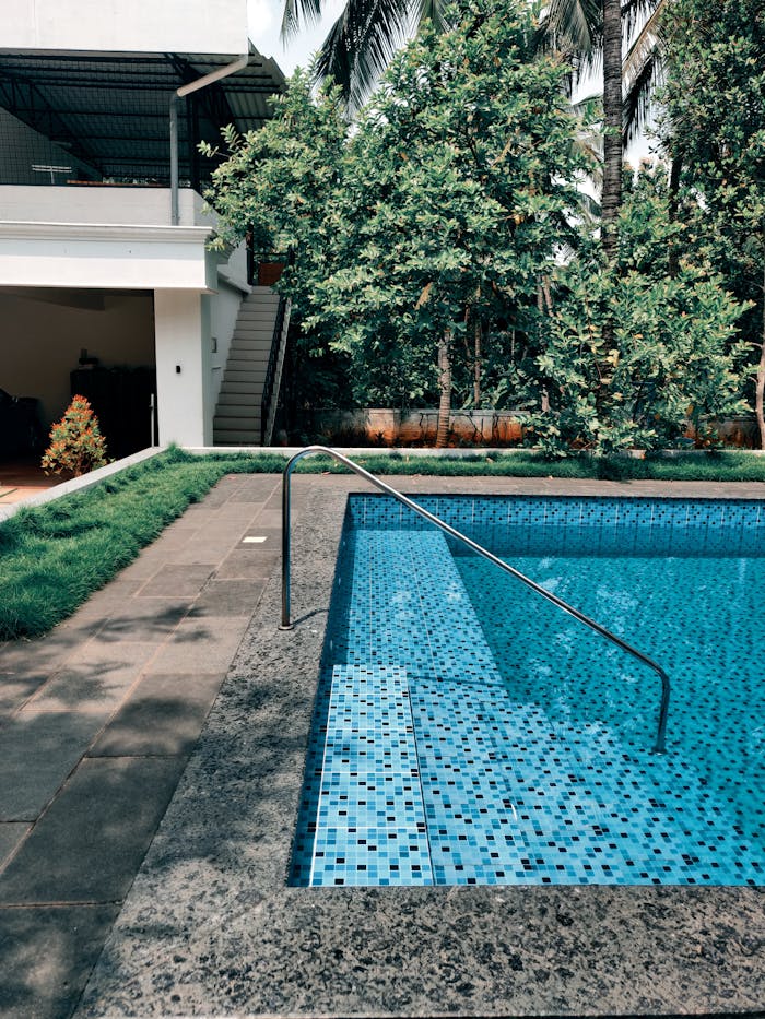 Elegant villa poolside area with lush greenery and modern design in Thootha, India.