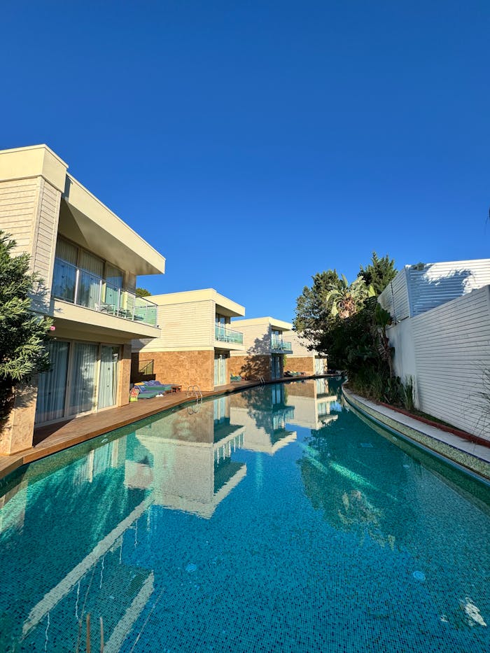 Contemporary villas surrounding a serene outdoor pool under clear blue skies.